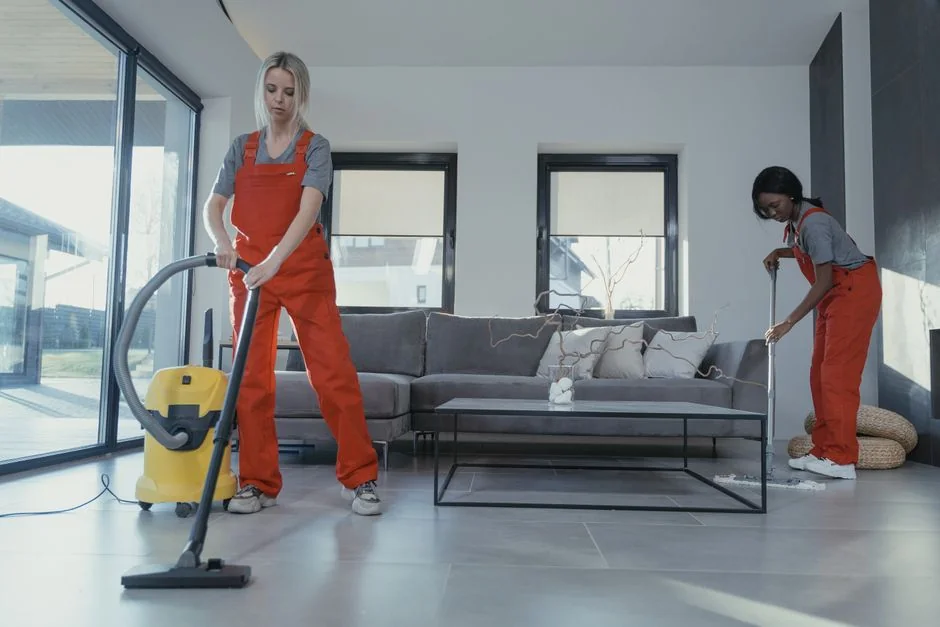 A woman carefully wraps a sofa in protective material while packing boxes in a bright room.